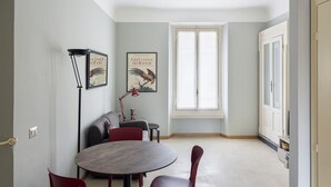 A dining area with a round table, red chairs, a sofa, and two framed pictures on the wall. - Hostmate - Milano - Cantoni - Washington  (Milano)