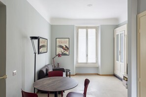 A dining area with a round table, red chairs, a sofa, and two framed pictures on the wall.