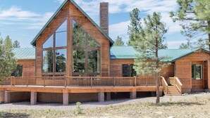 A modern log cabin with a large glass window, a wooden deck, and a chimney. - The EXECUTIVE LEVEL retreat for families and outdoor lovers in Happy Jack, AZ! (Happy Jack)