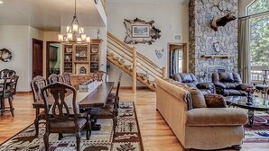 A spacious living room with a fireplace, a dining area with a chandelier, and a staircase leading to an upper level. - The EXECUTIVE LEVEL retreat for families and outdoor lovers in Happy Jack, AZ! (Happy Jack)