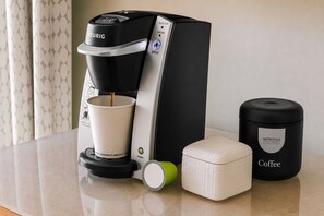 A Keurig coffee maker with a white cup, a green lid, and a black container labeled 'Metropolis Coffee' on a countertop.