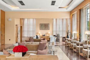 A hotel lobby with a reception desk, seating area, and a large window.