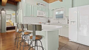 A modern kitchen with a central island, bar stools, a microwave, and a refrigerator. - Lakefront Home w/ Dock: 10 Mi to Central Ave! (Hot Springs)