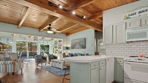A spacious living area with a large sofa, a dining table, and a kitchen with white cabinets and a central island. - Lakefront Home w/ Dock: 10 Mi to Central Ave! (Hot Springs)