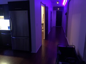 Leading to a space, this hallway features a door at the end, a refrigerator, and a cart.