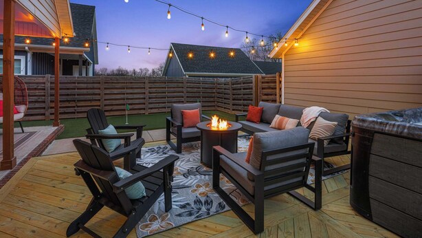 Eine Terrasse im Freien mit Holzmöbeln, einer Feuerstelle und Lichterketten.