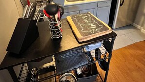 Eine Küche mit grauen Schränken, einem Edelstahlkühlschrank, einer Mikrowelle und einer Tafel mit Schrift.