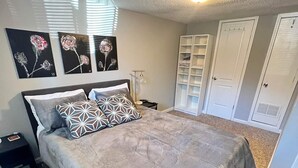 Ein Schlafzimmer mit einem großen Bett, einem Nachttisch, einer Lampe, einem Schrank und Wandbildern.