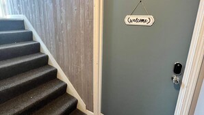 Eine Treppe führt zu einer Tür, über ihr prangt ein Schild mit der Aufschrift 'Welcome' und die Zahl 12.