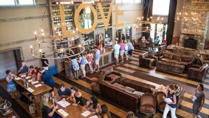 Een ruime lounge met verschillende zithoeken, een bar met gasten, en een groot decoratief 'LOVE'-bord.