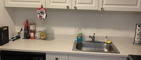 A kitchen with white cabinets, a stainless steel dishwasher, and a sink.