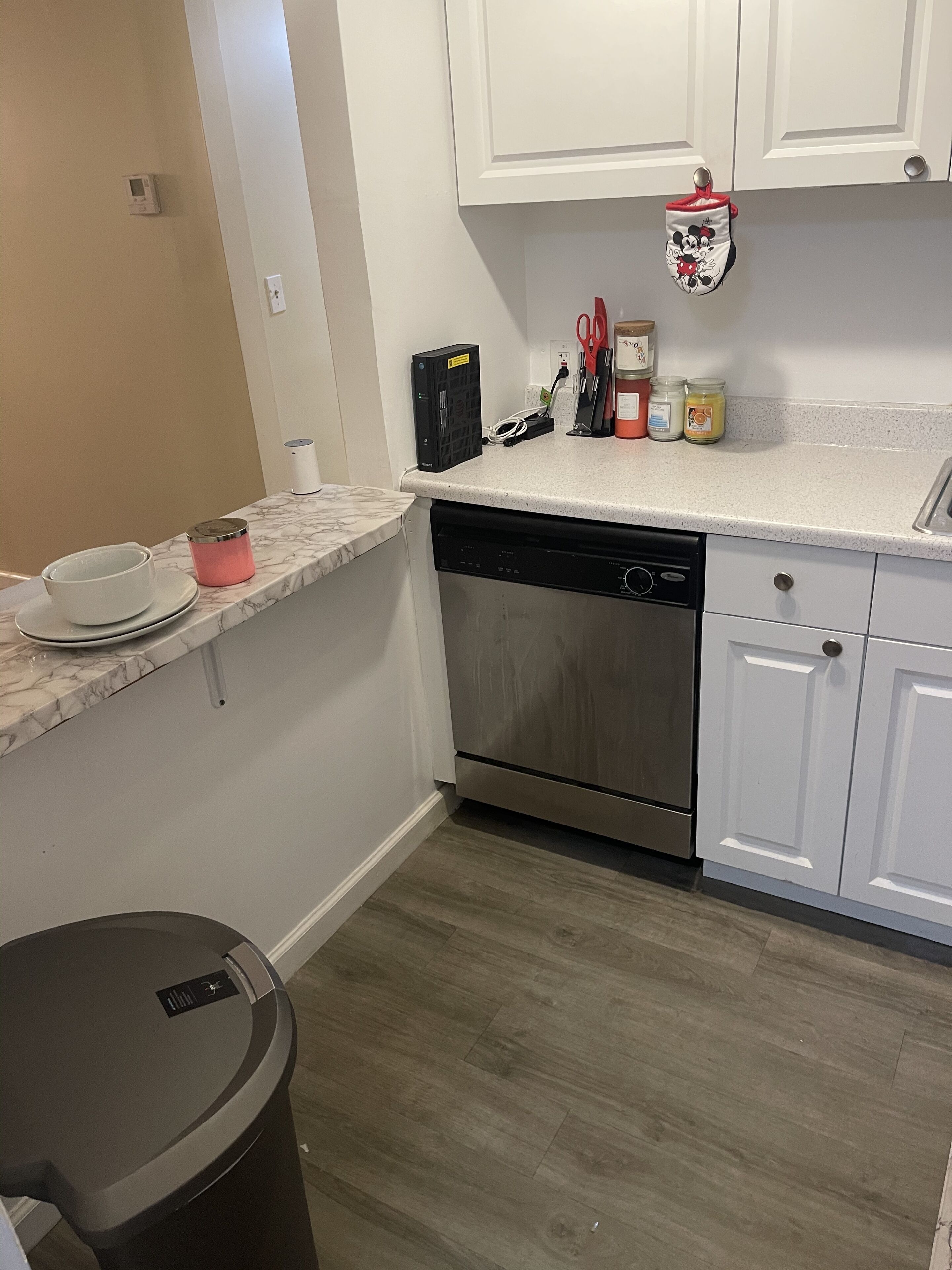 A kitchen with white cabinets, a stainless steel dishwasher, and a marble countertop.