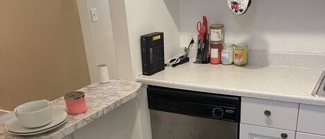 A kitchen with white cabinets, a stainless steel dishwasher, and a marble countertop.