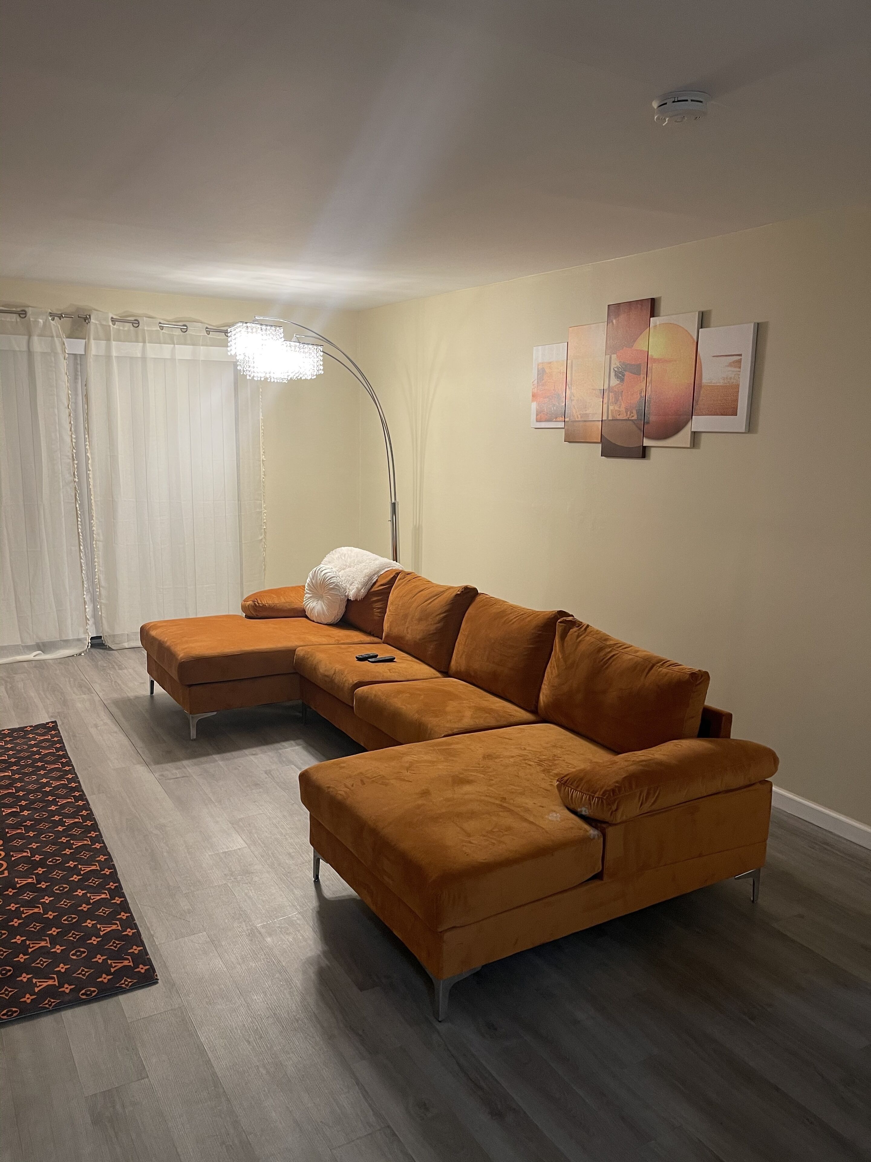 A living room with a sectional sofa, a floor lamp, and a patterned rug.