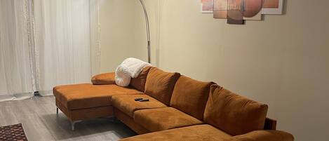 A living room with a sectional sofa, a floor lamp, and a patterned rug.