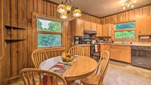 Een houten keuken in cottage-stijl met een eettafel, stoelen en een mand met fruit.