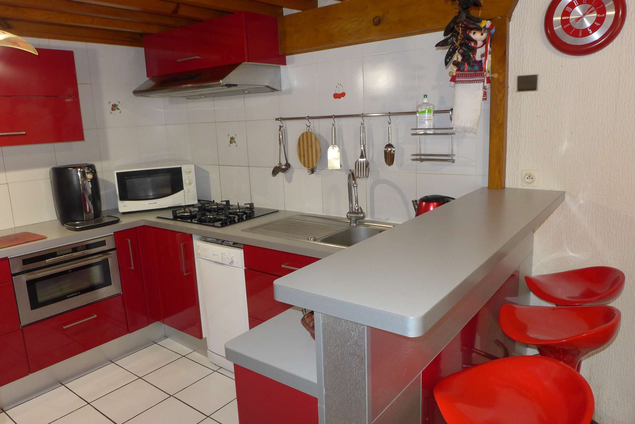 A kitchen with red cabinets, a microwave, a stove, and a sink.