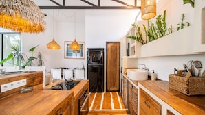A kitchen with wooden countertops, a central island, hanging pendant lights, and a backsplash with greenery. - Private Pool Courtyard | Three Suites | Cafe Walk (Kerobokan)