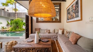 Ein modernes Wohnzimmer mit einer großen Couch, einem Holztisch und einer Pendelleuchte.