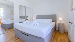 Une chambre d’hôtel moderne avec un grand lit, une table de chevet avec une lampe, un miroir et un radiateur.