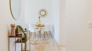 Un espace repas moderne avec une table ronde, des chaises blanches et un miroir décoratif au mur.