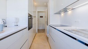 Une cuisine moderne avec des meubles blancs, un four encastré, un four à micro-ondes et un grand plan de travail.