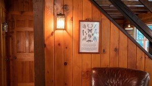 Een houten interieur met een lederen stoel, een lijst met een poster en een deur.