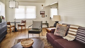 A living room with a wooden floor, a sofa, a chair, a table, and a lamp.
