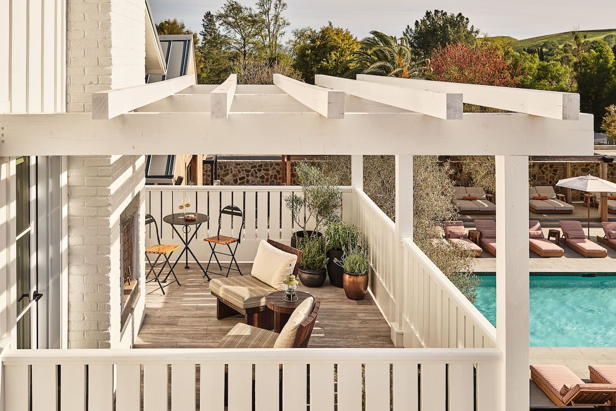 A covered outdoor area with a pool, lounge chairs, and a wooden deck.