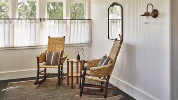 A room with two wicker chairs, a small round table, and a mirror on the wall.