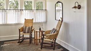 A room with two wicker chairs, a small round table, and a mirror on the wall.