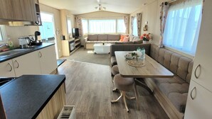 A well-lit RV interior with a kitchenette, dining area, and seating space. - St Osyth- Sleeps8-freeparking-wifi-holidaypark (Clacton-on-Sea)