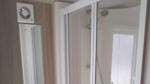 Ein Badezimmer mit Duschkabine, Waschbecken und Spiegel.