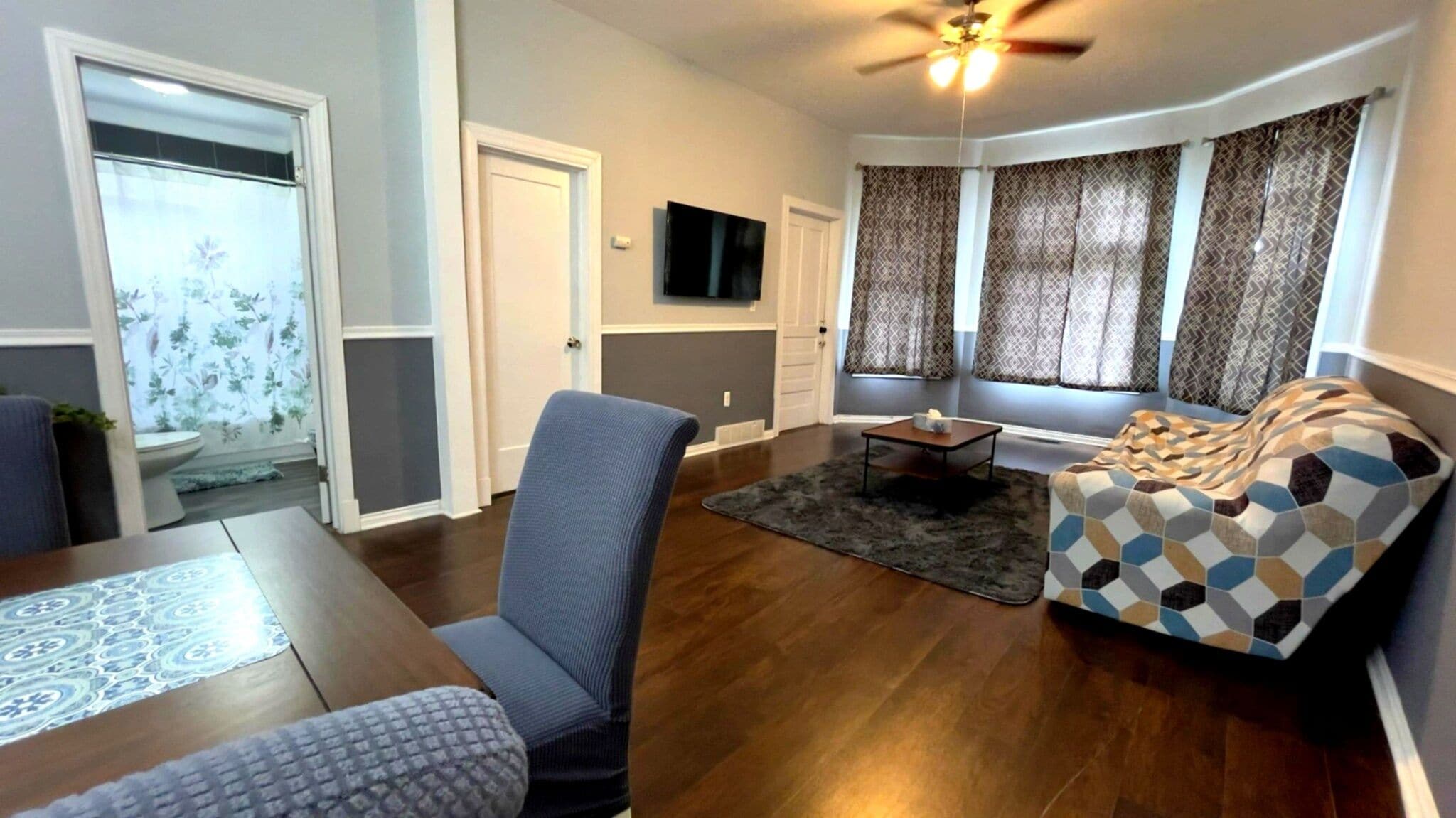 A living room with a sofa, armchair, coffee table, and a television.