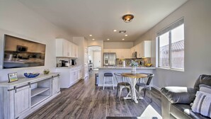 A modern kitchen with white cabinets, a central island, and a dining area with a leather couch and chairs. - Hike & Golf: Goodyear Retreat w/ Patio + Fire Pit! (Goodyear)