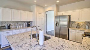 A modern kitchen with white cabinetry, granite countertops, stainless steel appliances, and a central island with a sink. - Hike & Golf: Goodyear Retreat w/ Patio + Fire Pit! (Goodyear)