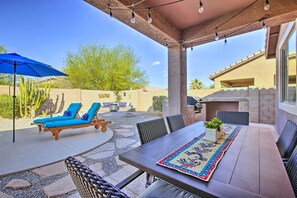 An outdoor patio with a table, chairs, and a blue umbrella.