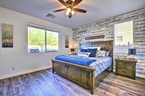 Une chambre avec un lit en bois, un ventilateur de plafond et une fenêtre avec des stores.