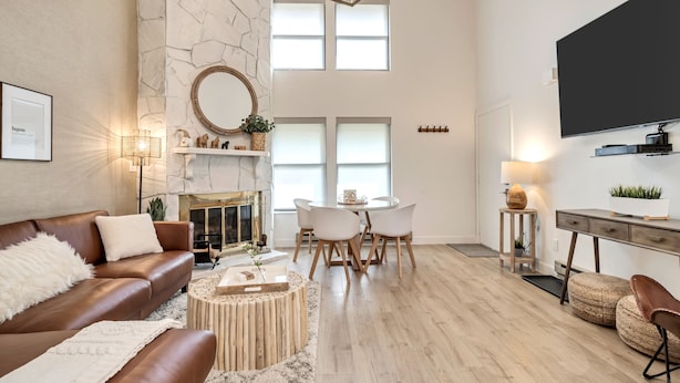 A spacious living room with a fireplace, a dining area, and a kitchen with a large flat-screen TV.