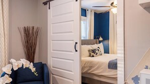 A bedroom with a bed, a chair, and a sliding door leading to another room.