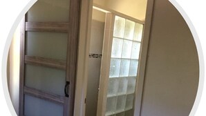 A bathroom with a glass shower enclosure, a toilet, and a wooden door with frosted glass panels. - Veronica's Villa (St Thomas)