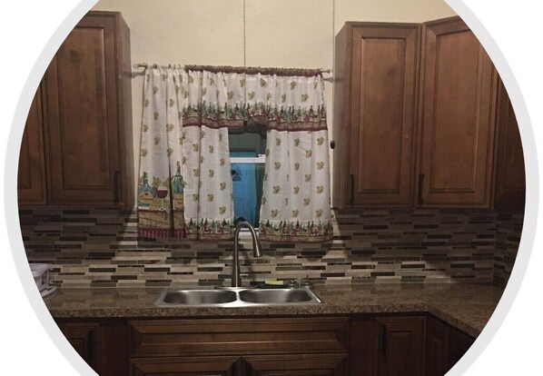 A kitchen with wooden cabinets, a tiled backsplash, and a double sink.