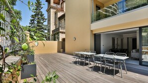 A modern outdoor patio with a wooden deck, white metal tables and chairs, and a glass balustrade overlooking a cityscape. - T3 Large Terrace "Capo di Feno" (Ajaccio)