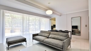 A modern living room with a sofa, a coffee table, and a dining area with a TV. - T3 Large Terrace "Capo di Feno" (Ajaccio)