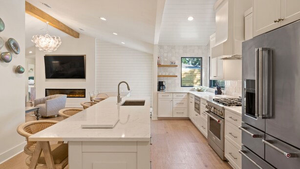 Una cocina moderna con una isla grande, electrodomésticos de acero inoxidable y una chimenea.