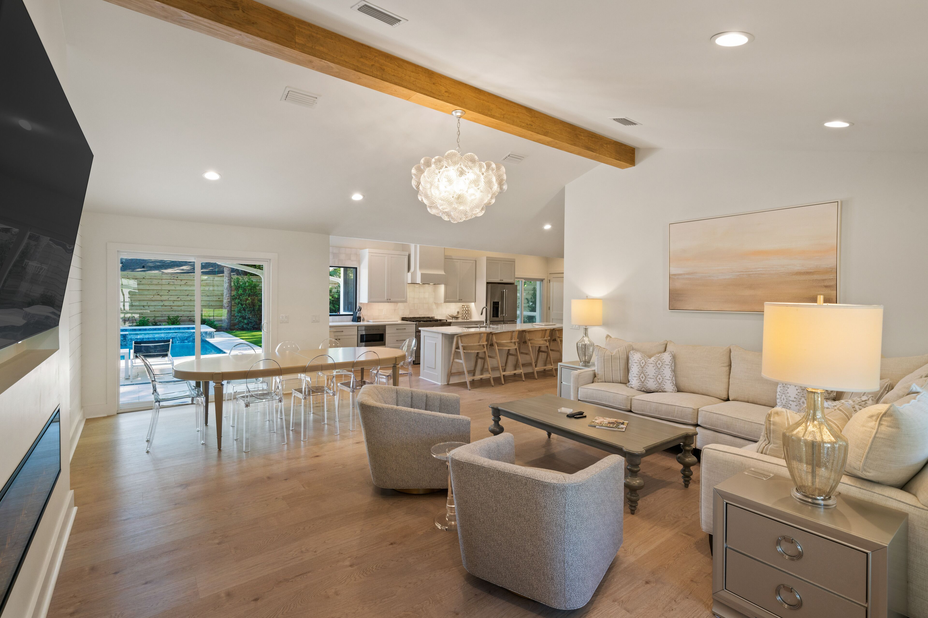 A spacious living area with a dining table, sofas, and a kitchen in the background.