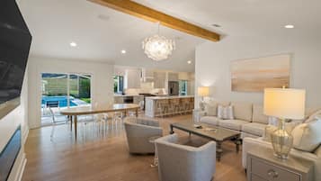 A spacious living area with a dining table, sofas, and a kitchen in the background.