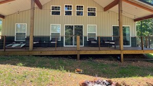 A large building with a covered deck area, multiple windows, and a wooden railing.