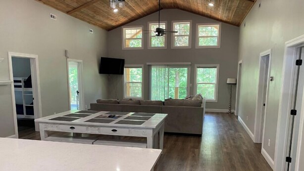 A spacious living area with a large island table, a sofa, and a ceiling fan.