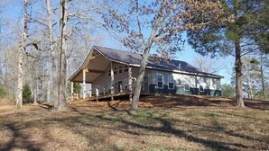 A two-story house with a porch, surrounded by trees.
